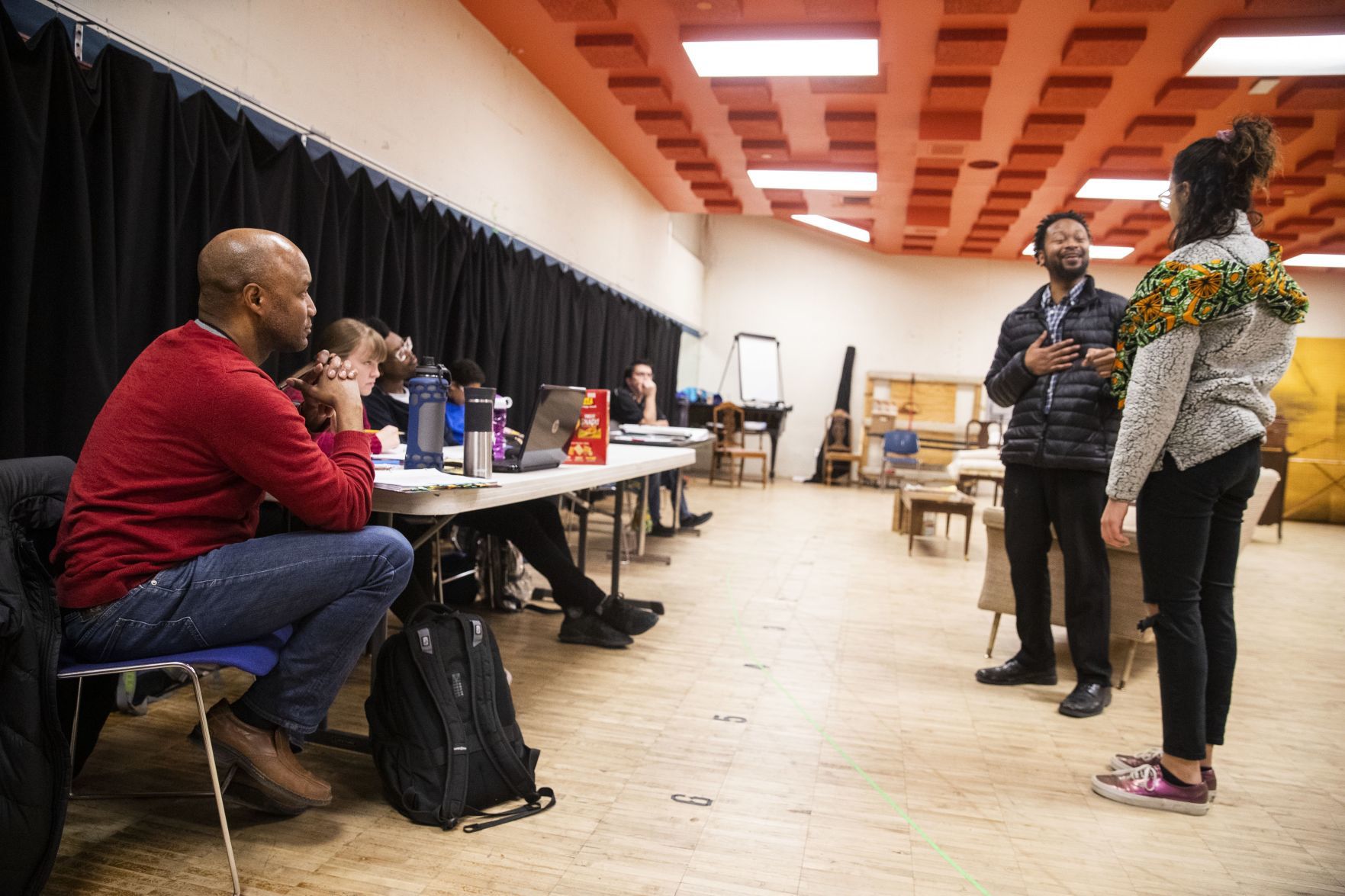 Tyrone Beasley looks on while directing the play 'A Raisin in the Sun' with cast members Donté Plunkett performing as Joseph Asagai and Olivia Howard performing as Beneatha Younger